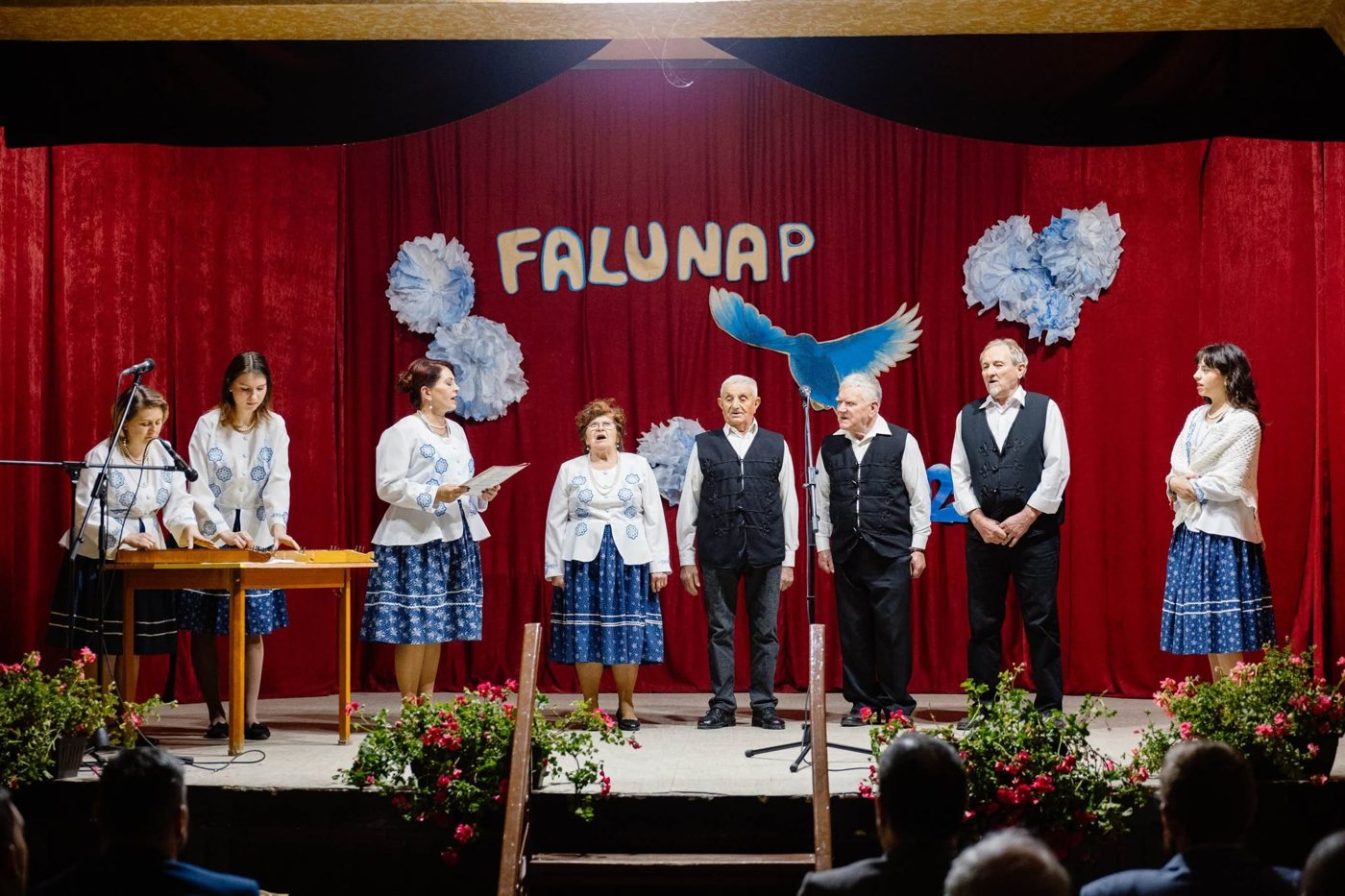 Népviseletbe öltözött énekesek és citerások lépnek fel az oromi falunapon 2025-ben, a színpad hátterében a Falunap felirattal