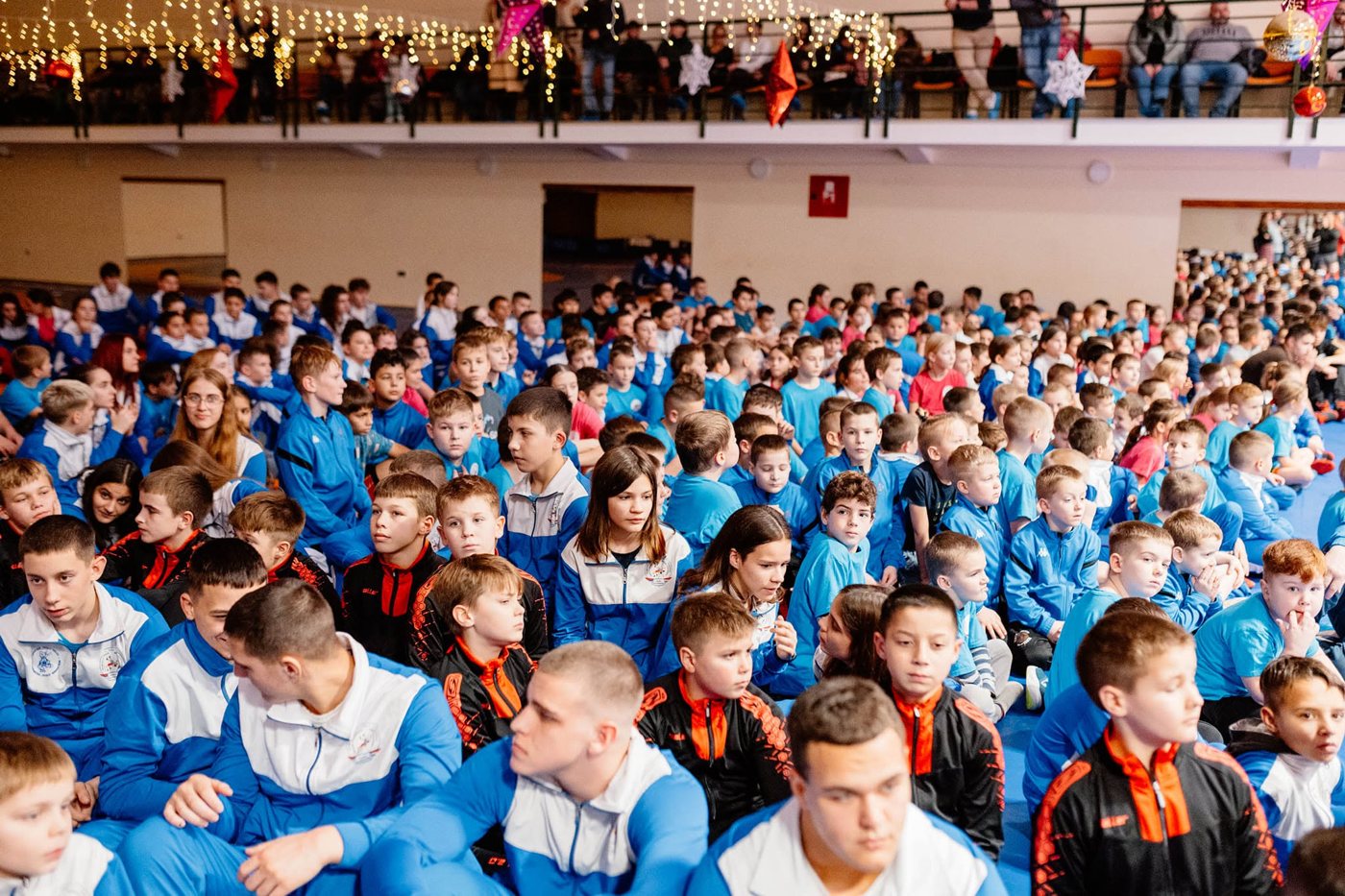 Sportmezes gyerekek százai ülnek egy sportcsarnokban