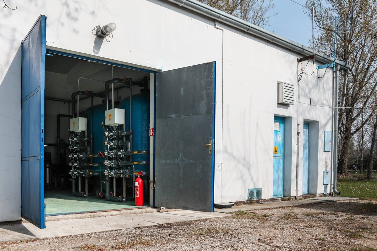Víztisztító épület nyitott ajtóval, bent kék szűrőtartályok